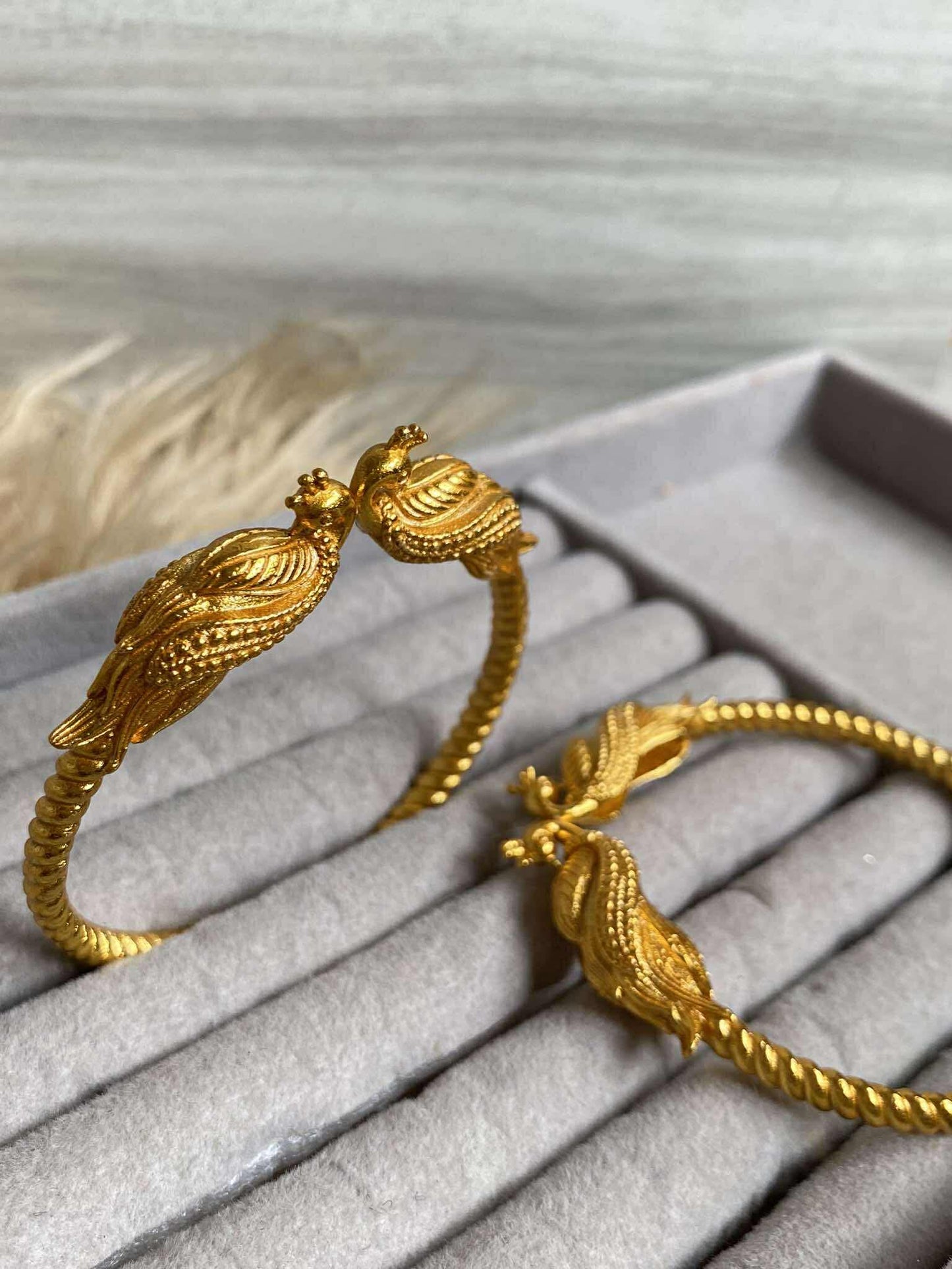 Gold bracelet with intricate design on a gray surface