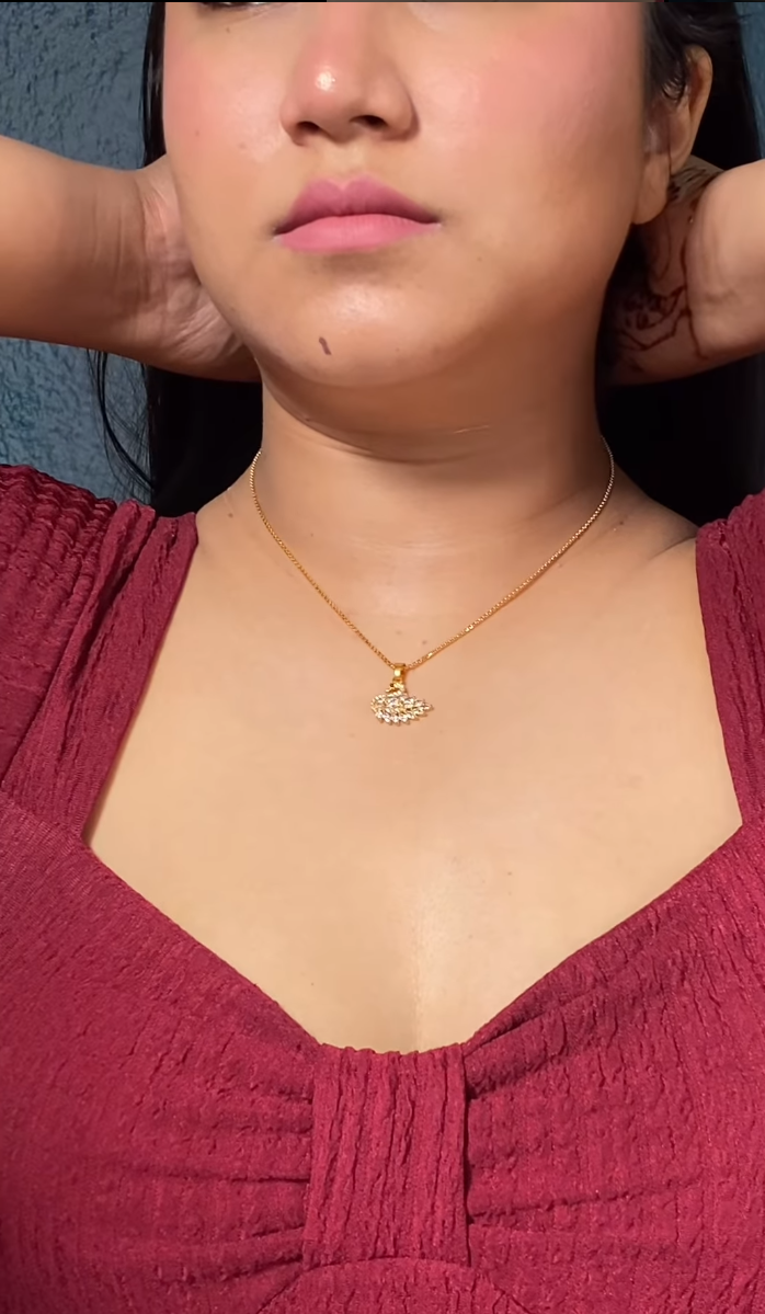 A person wearing a swan-shaped gold pendant on a red dress.