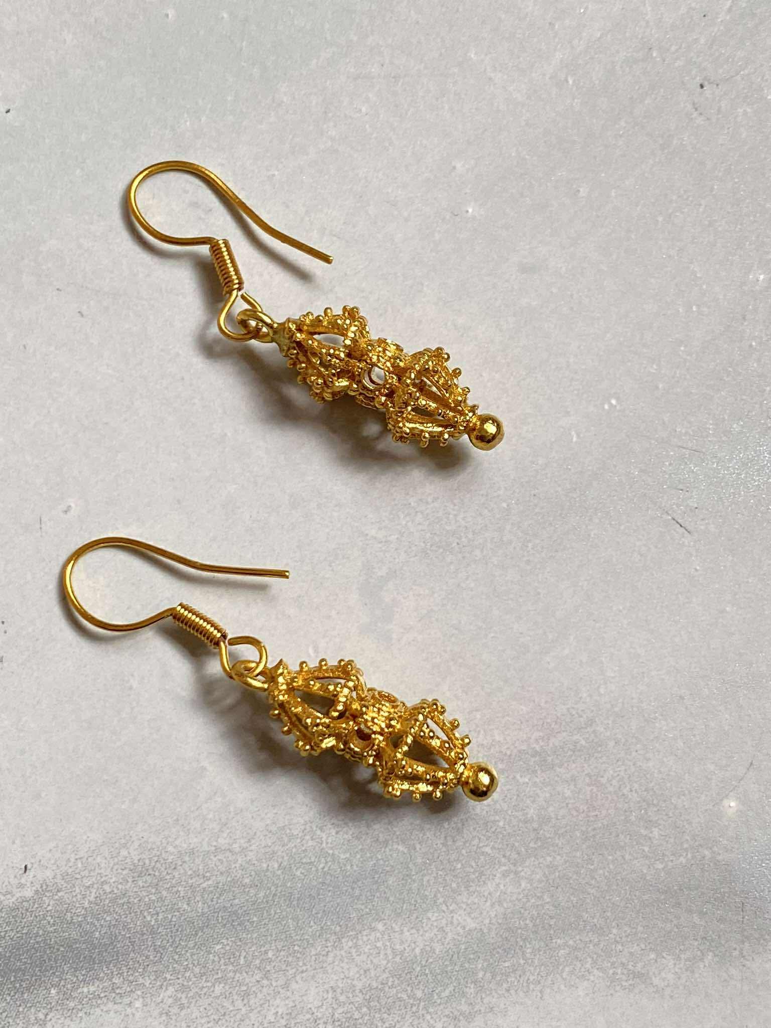 Pair of gold earrings on a light gray background