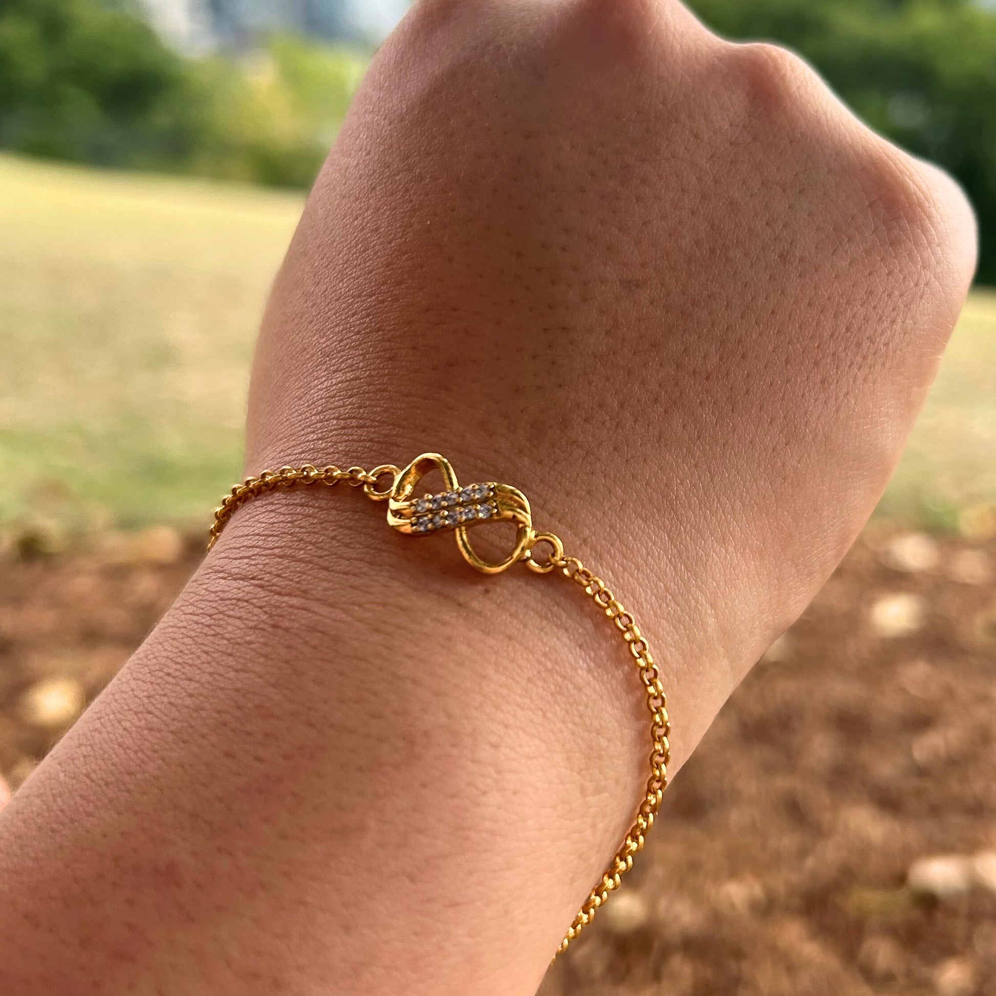 Gold bracelet on a wrist with a blurred natural background