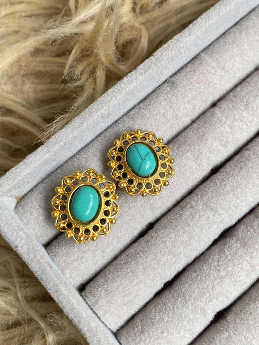 Turquoise earrings with gold frames on a gray surface