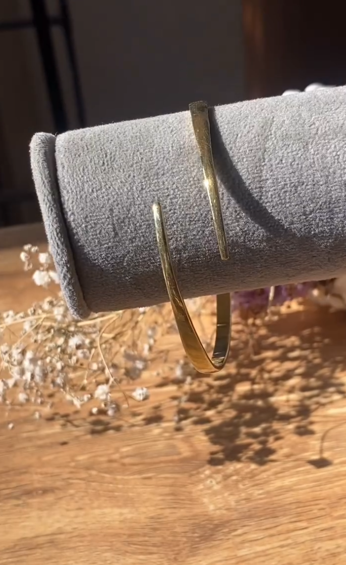 The Eloise Bangle is defined by its graceful open form and gentle taper, creating a refined silhouette that sits lightly on the wrist. Its polished finish catches the light with a soft glow, adding an effortless elegance to your everyday style. A modern classic that feels both delicate and confident, designed to be worn with ease and intention.