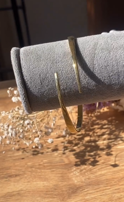 The Eloise Bangle is defined by its graceful open form and gentle taper, creating a refined silhouette that sits lightly on the wrist. Its polished finish catches the light with a soft glow, adding an effortless elegance to your everyday style. A modern classic that feels both delicate and confident, designed to be worn with ease and intention.