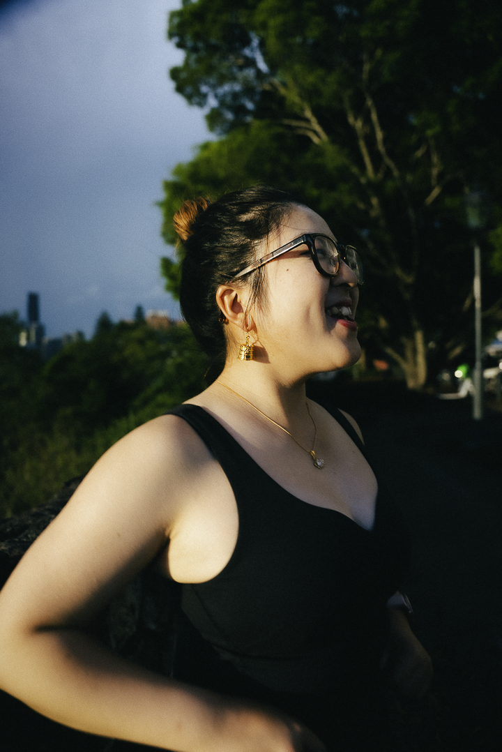 Woman wearing Kala:Cha Earrings and a black top outdoors with trees in the background