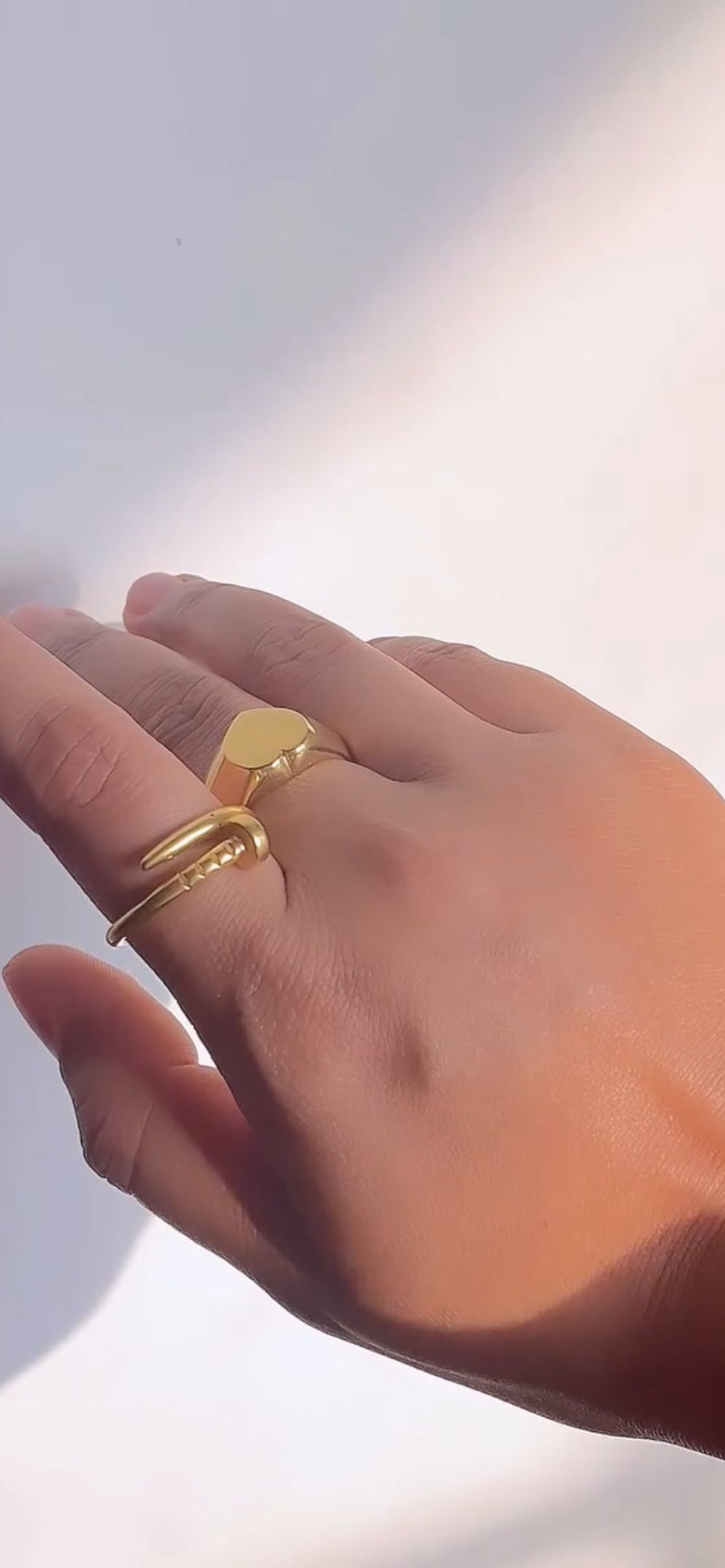 Hand wearing a gold ring on a light background