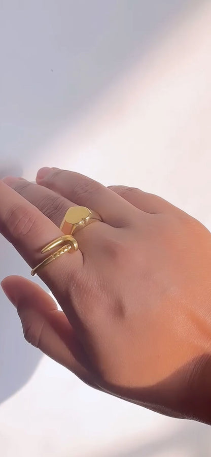 Hand wearing a gold ring on a light background
