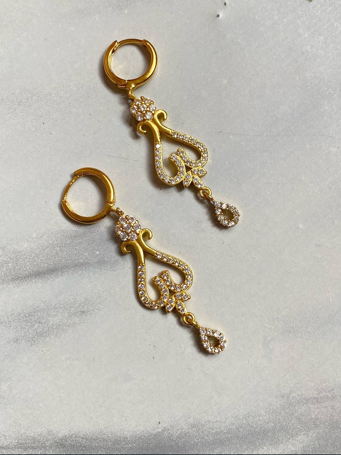 Ashwini Earrings with intricate designs on a light gray background