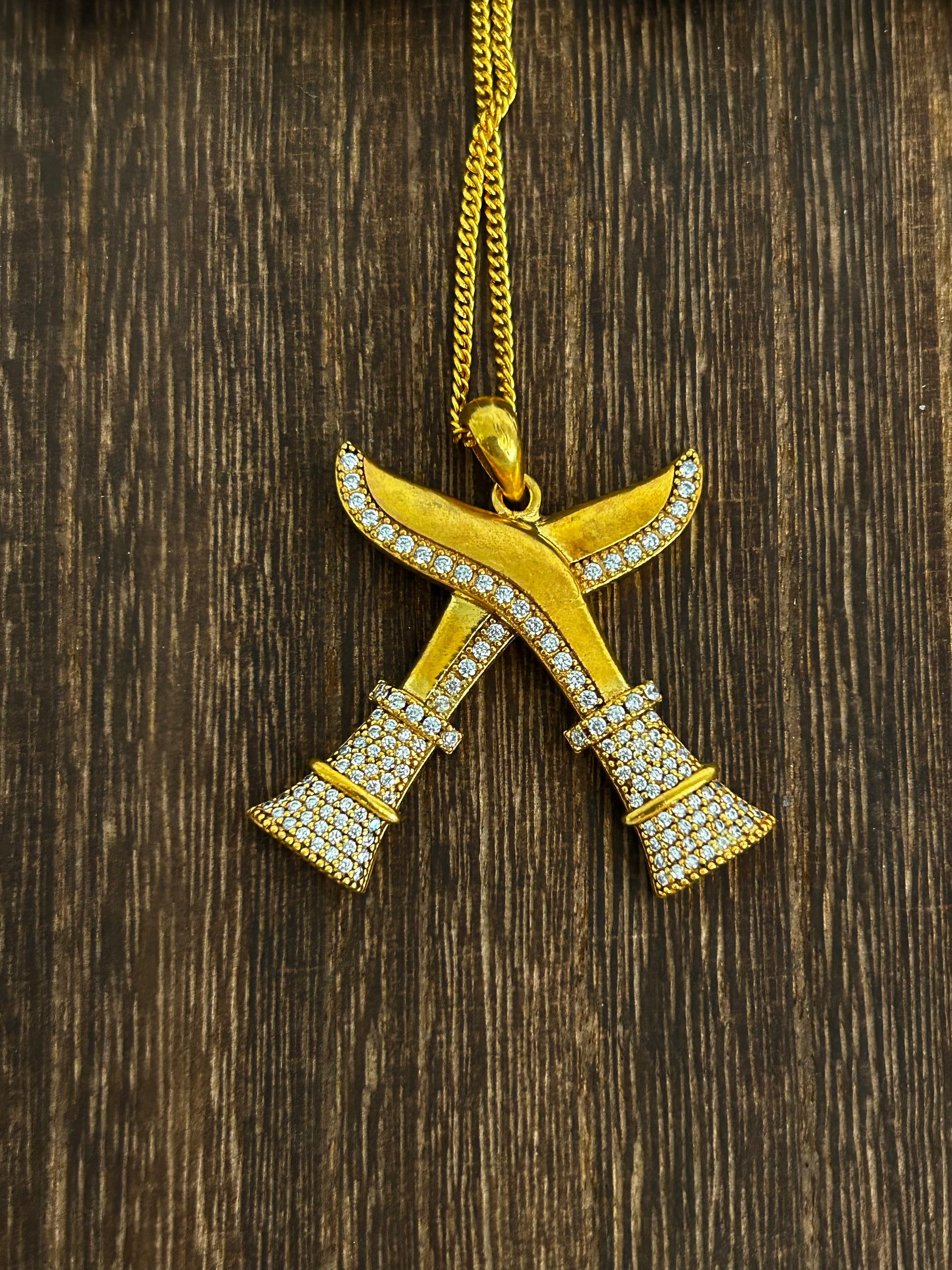 Khukuri pendant with chain on a wooden surface