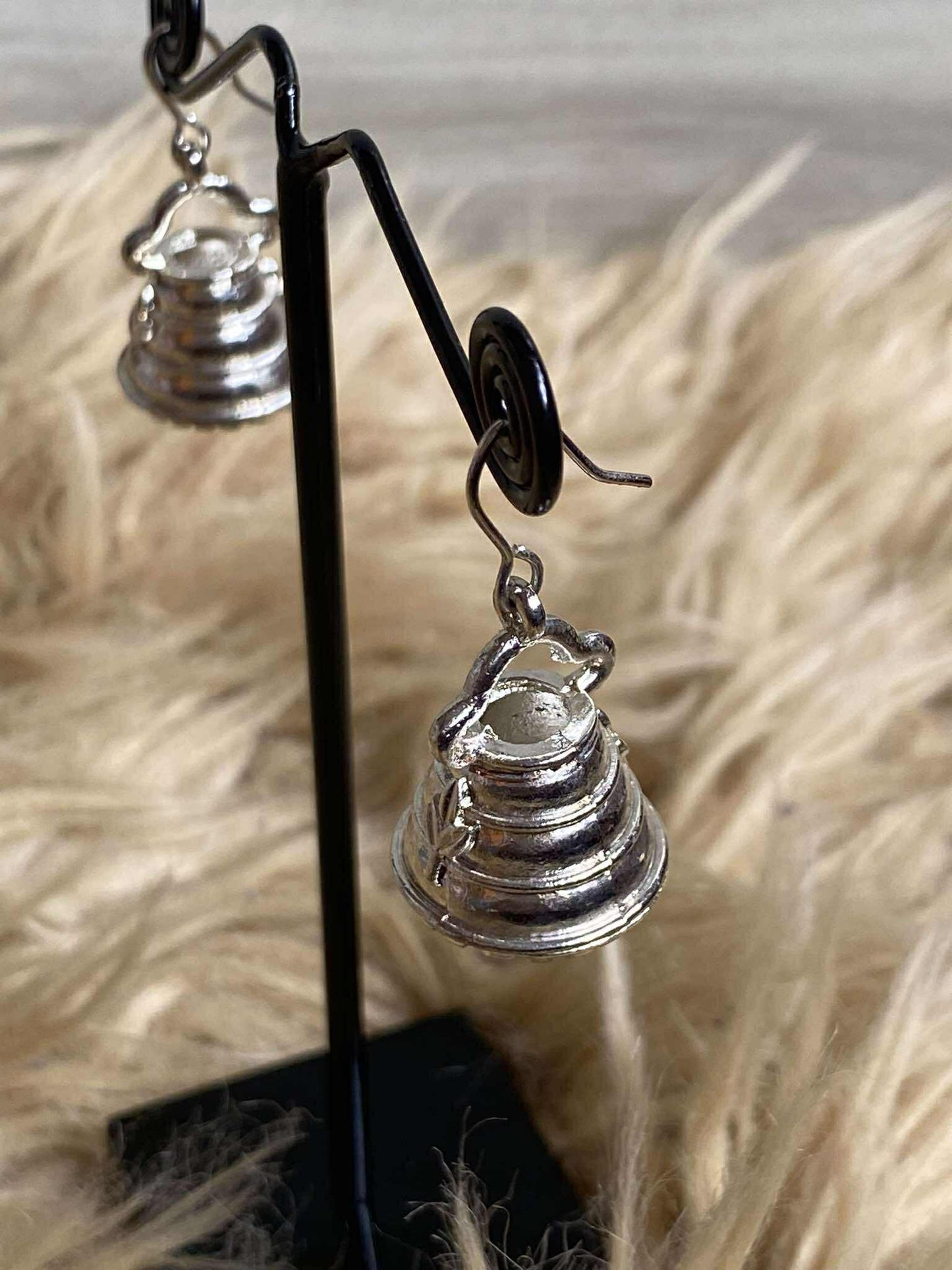 Silver earrings on a stand with a neutral background