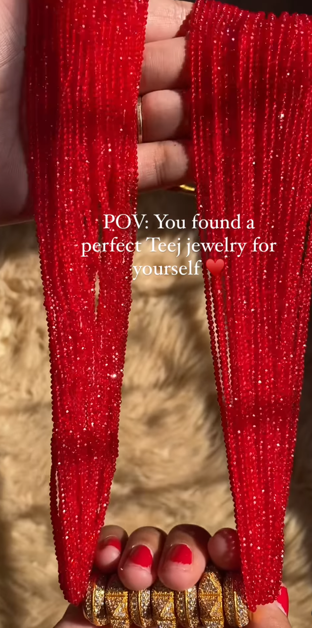 A person holding a red and gold traditional Teej Tehari jewelry piece.