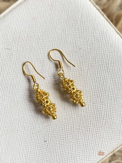 Gold earrings on a textured fabric surface