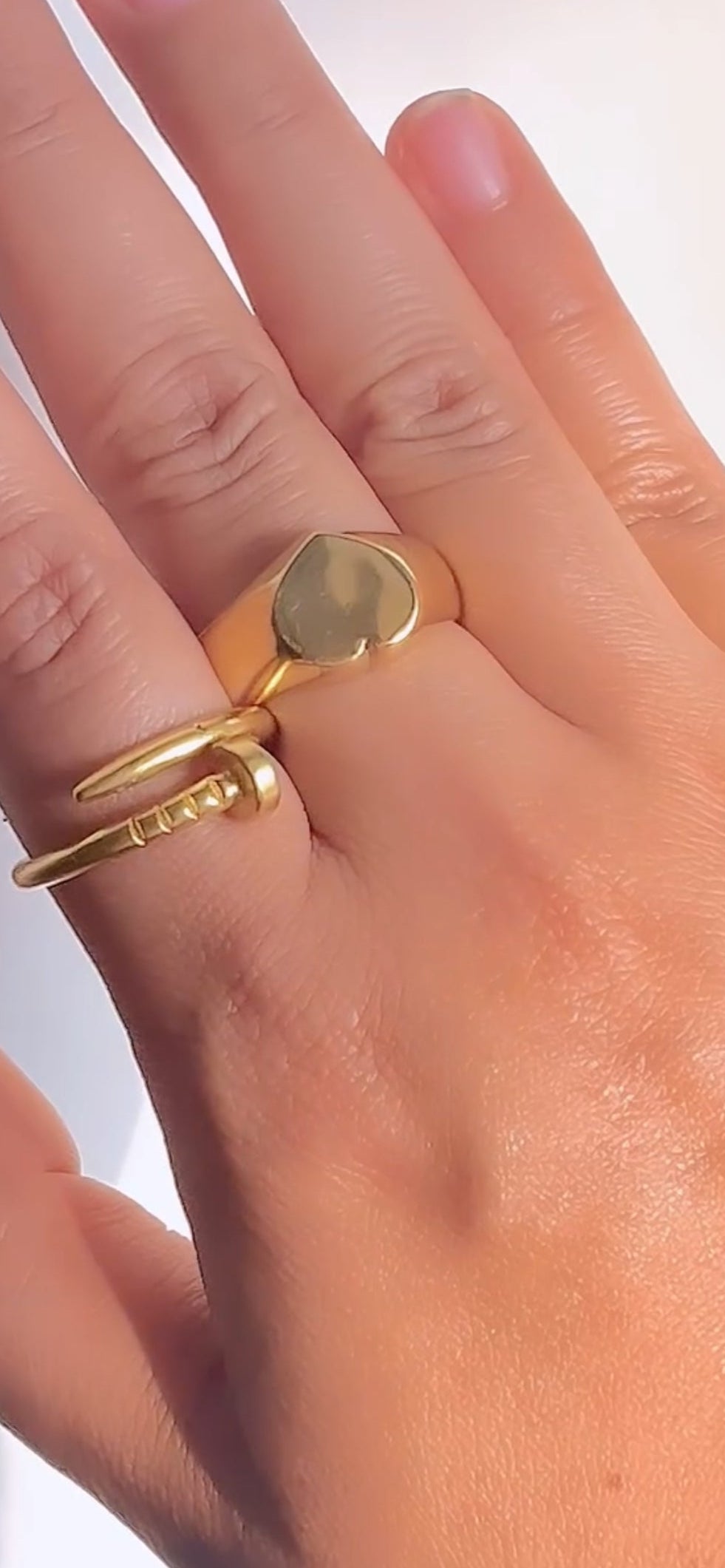 Gold ring on a finger against a neutral background