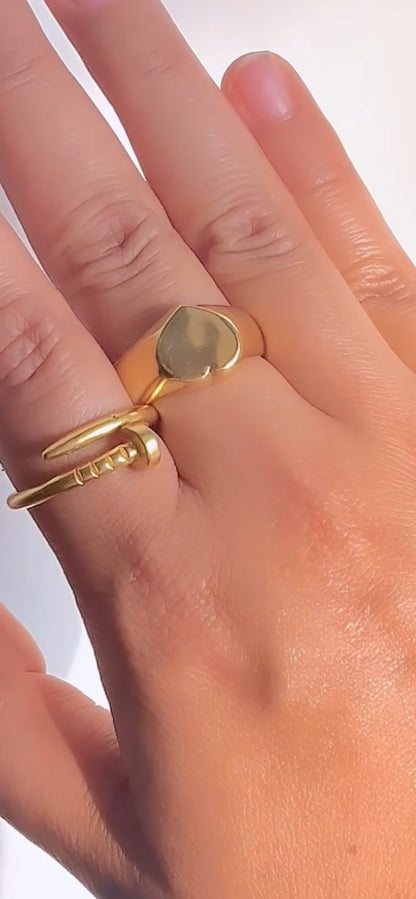 Gold ring on a finger against a neutral background
